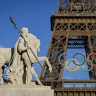 Olympic rings are seen on the Eiffel Tower near the restored statue of 