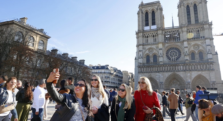 PARIS, FRANCE - OCTOBER 25: Tourists take a selfie with Notre-Dame de Paris Cathedral a few weeks before its reopening to the public scheduled for December 7, 2024 on October 25, 2024 in Paris, France. French ministers have floated the idea of â€‹â€‹charging tourists to enter the world-famous Notre Dame Cathedral in Paris when it opens on December 7 after five years of restoration. 